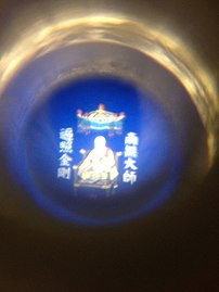 A prayer bead containing an image of Kūkai flanked by a devotional mantra
