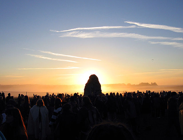 Солнце за камнем Стоунхенджа на рассвете в день летного солнцестояния, Великобритания