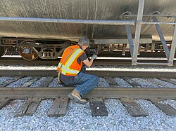 An FRA hazardous materials inspector examines outlet valves at the bottom of a tank car to ensure that they are properly tightened Tank car valve inspection.jpg