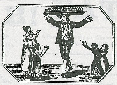 Engraving of a man selling sausage rolls, from a tray balanced on his head. A woman holding a toddler, with three other children, wait to buy. They all wear period clothing