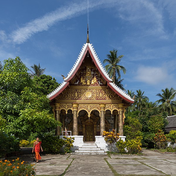 File:Vat Pa Phai temple with a Buddhist monk, orange marigold, clouds and blue sky, in Luang Prabang.jpg