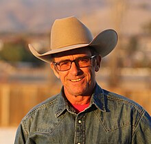 a head and shoulders image of warwick schiller wearing a cowboy hat and smiling