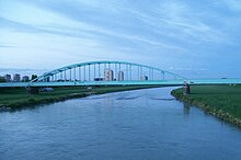 Fluss unter Brücke mit Stadt im Hintergrund