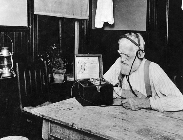 Farmer listening to U.S. government weather and crop reports using a crystal radio in 1923. Public service government time, weather, and farm broadcas
