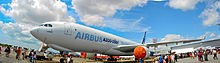 En A330-200F i Airbus' hvide og blå farver fremvises under en delvist overskyet men ellers klar himmel. Motorindsugningerne er dækket til.