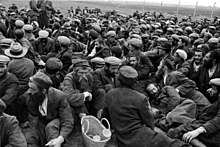 Captive Jews from Krakow Ghetto await slave labour on an open field behind barbed wire, 1939 Bundesarchiv Bild 121-0296, Krakau, Judenlager.jpg