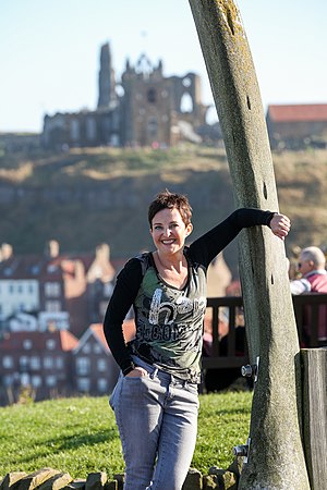 Female Figure Standing in front of the whale bones on West Cliff in Whitby. Abbey in the background