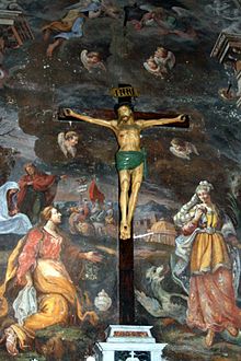 Fresque montrant des personnages religieux. Un autel avec une crucifixion devant la fresque.