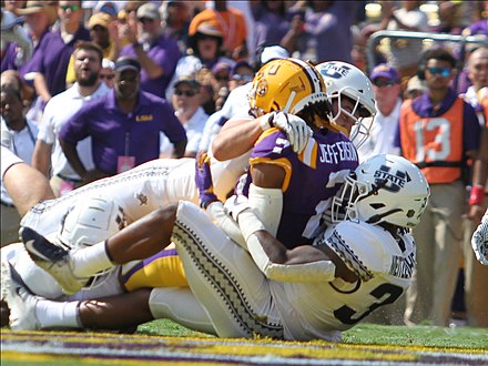 Utah State players tackling a Louisiana State football player in 2019