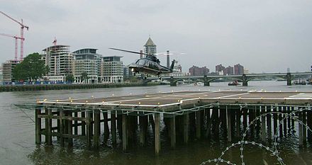 A Sikorsky S-76 landing at London Heliport. Battersea Railway Bridge is seen in the background.