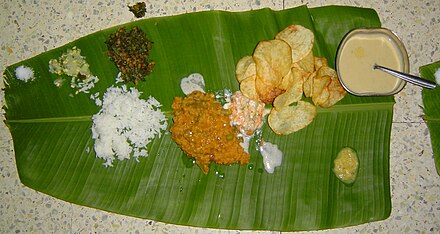 A typical lunch from Karnataka contains white rice, cucumber salad, potato chips, poppy sweet, lentils, yoghurt and bisibele bath.