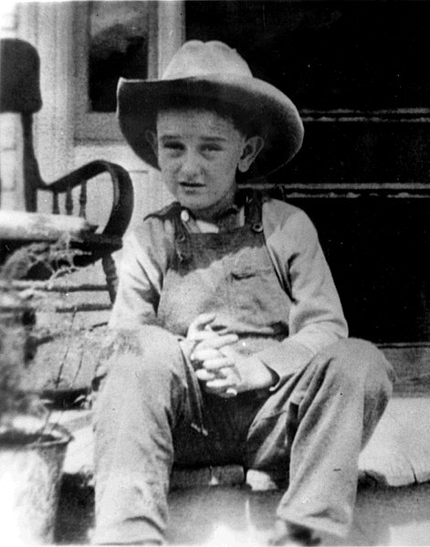 A seven-year-old Johnson, wearing his trademark cowboy hat, at his childhood farmhouse near Stonewall, Texas, in 1915