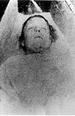 Photographie mortuaire en noir et blanc d'une femme aux cheveux courts et au nez proéminent.
