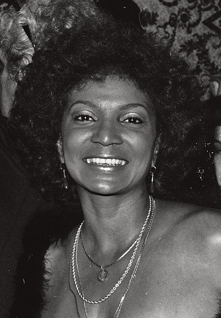 A grinning afro-haired Nichelle Nichols