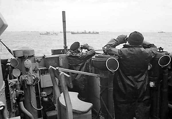 Royal Navy officers on the bridge of a destroyer on convoy escort duties keep a sharp look out for enemy submarines during the Battle of the Atlantic,