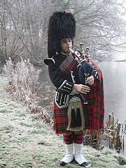 Piper playing the Great Highland Bagpipes in traditional Scottish piper's uniform (2010)[a]