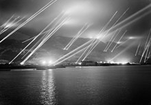 Le rocher de Gibraltar, vu de l'ouest, avec au moins 23 projecteurs envoyant des faisceaux de lumière dans le ciel nocturne