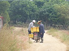 A farmer in his field buys his breakfast from a motorcycle-based traveling vendor. Zhangpu County, Fujian, China. Shentu - rural landscape east of Shanwei cun - P1260065.JPG