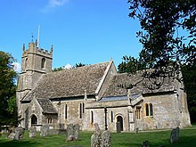 A photograph of a stone church with a tower and a tiled roof.
