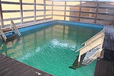 Interior of a wooden structure containing a spa pool, with people