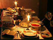 Une table recouverte d'un drap blanc et sertie d'une Bible ouverte, de bougies et de plats de divers aliments