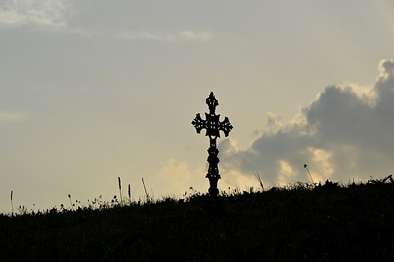 A silhouette of a cross on a cemetery