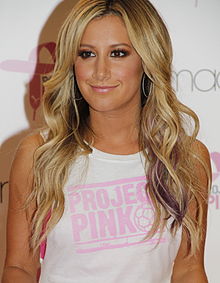 A photo of Ashley Tisdale at Macy's Herald Square NYC in July 2012. Attending a Puma Project Pink event, she wears a white sleeveless shirt with the event's logo printed on it.