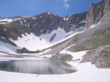 Cima Redentore dal sottostante lago di Pilato, a destra si scorge la parete del Pizzo del Diavolo