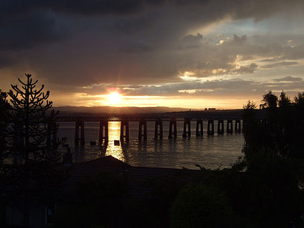 The current Tay Bridge at dusk, with the masonry of one of Bouch's piers silhouetted against the sunlit water