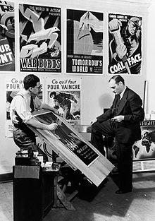 John Grierson (right), National Film Board (NFB) Commissioner, and Harry Mayerovitch, director of the Wartime Information Board's (WIB) Graphic Arts Division, examine posters in 1944. Grierson & Mayerovitch.jpg