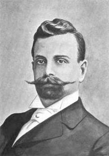 Man in a suit with a large moustache and goatee