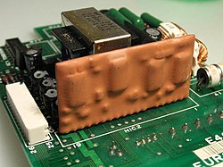 An (orange-epoxy) encapsulated hybrid circuit on a printed circuit board. Hybridcircuit.jpg