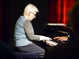 une femme âgée, cheveux blancs, au piano