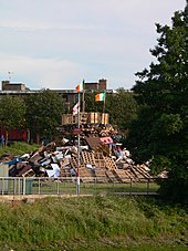 Ulster loyalists prepare to burn the Irish flag on a bonfire on the eve of The Twelfth in Belfast. Irish flag on bonfire.JPG