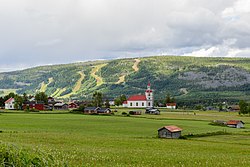 Juni 2014 Ansicht von Klövsjö mit Klövsjö-Kirche und den Skihügeln im Hintergrund