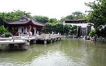 A pagoda on a pond with a waterfall.