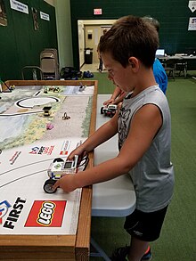 Child tests a robot built at a hands-on LEGO day camp in Maine. LEGO robot camp.jpg