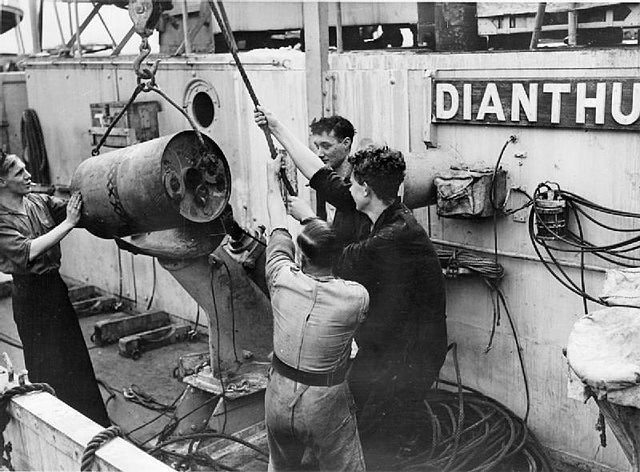 A depth charge thrower being loaded, aboard corvette HMS Dianthus, 14 August 1942