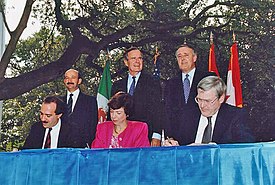 NAFTA Initialing Ceremony, October 1992.  From left to right: (standing) President Carlos Salinas, President Bush, Prime Minister Brian Mulroney; (seated) Jaime Serra Puche, Carla Hills, Michael Wilson.