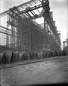 Olympic under construction, c. 1909. The Arrol Gantry can be seen towering over the ship. Titanic's keel is visible to the left Olympic under construction.JPG