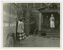 Photograph of Mrs. Asbell, a housewife with an invalid husband, coming out to meet the Athens Regional Library bookmobile in Athens, Georgia, September 1948. Photograph of the Athens Regional Library bookmobile, Athens, Georgia, 1948 September - DPLA - f14b48f318bf6b4dcc9bcd2df89372e0.jpg