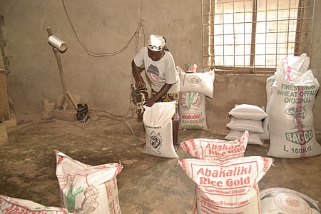 A woman bagging the milled rice using a simple machine for onward transportation to the market