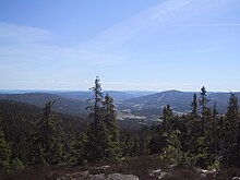 Foto eines Ausblicks auf ein Tal umgeben von bewaldeten Hügeln