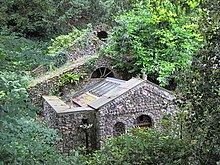 Exterior of Scott's Grotto, a house-shaped building covered in stones and sea shells, surrounded by trees