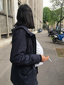 En mörkhårig gravid kvinna som röker i Paris.