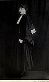 A full-length, black and white photograph of a woman wearing judicial robes