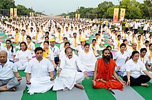 A guru leads a large group in outdoor meditation