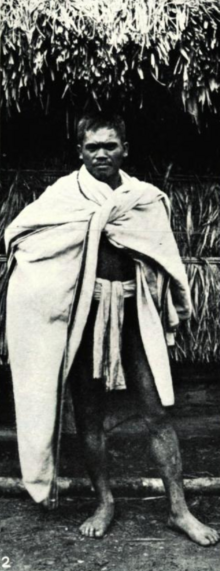 A Kankanaey man from Irisan, Baguio, in typical attire. Note the large blanket worn over the shoulders (c. 1906) Typical Benguet-Lepanto Igorot man of Iresan, Benguet (1906).png