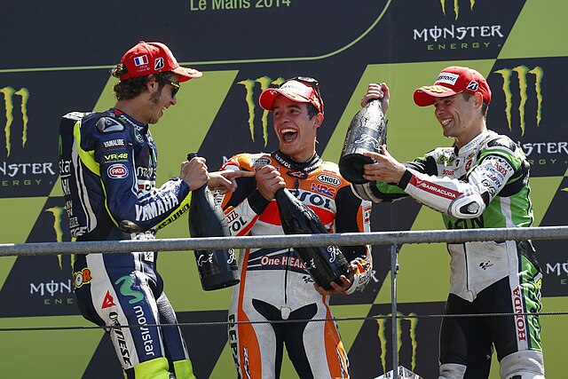Valentino Rossi, Marc Márquez and Álvaro Bautista, toasting the champagne on the podium after finishing second, first and third in the MotoGP race.