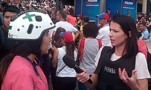 Abby Martin interviewing a member of the Green Cross [es] during the 2017 Venezuelan protests Abby Martin Venezuela.jpg